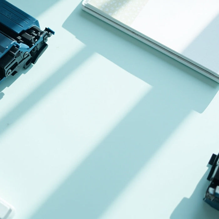 neatly arranged office supplies and toner cartridges on a sunlit, modern workspace desk